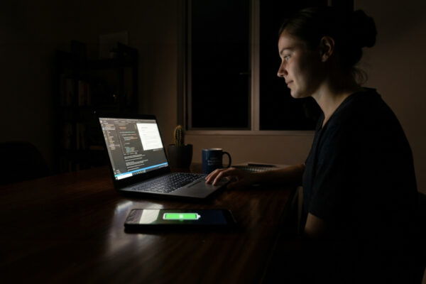 Woman working on a refurbished laptop by screen light during load shedding